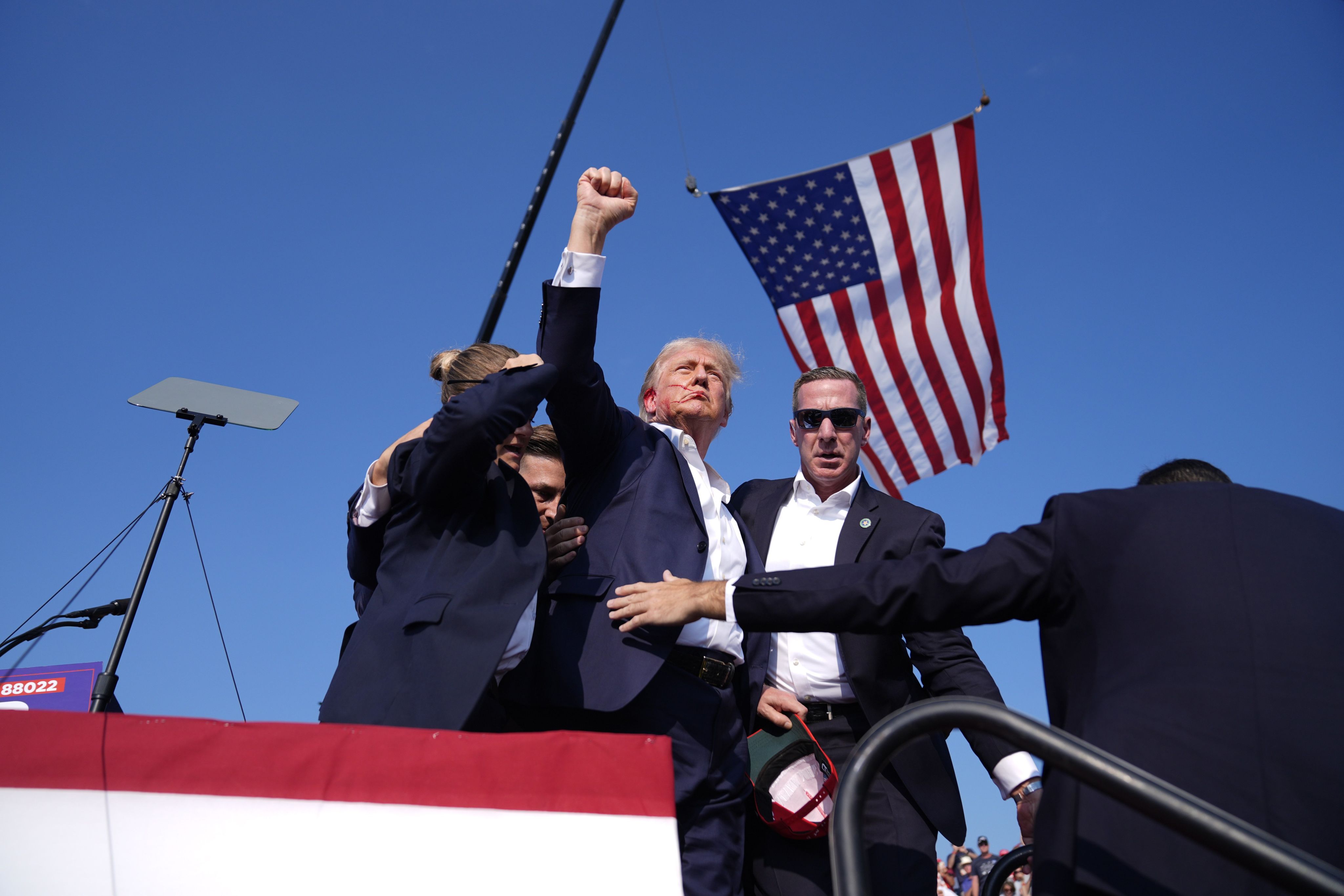 Donald Trump raises a fist in the air as he's escorted off stage by Secret Service