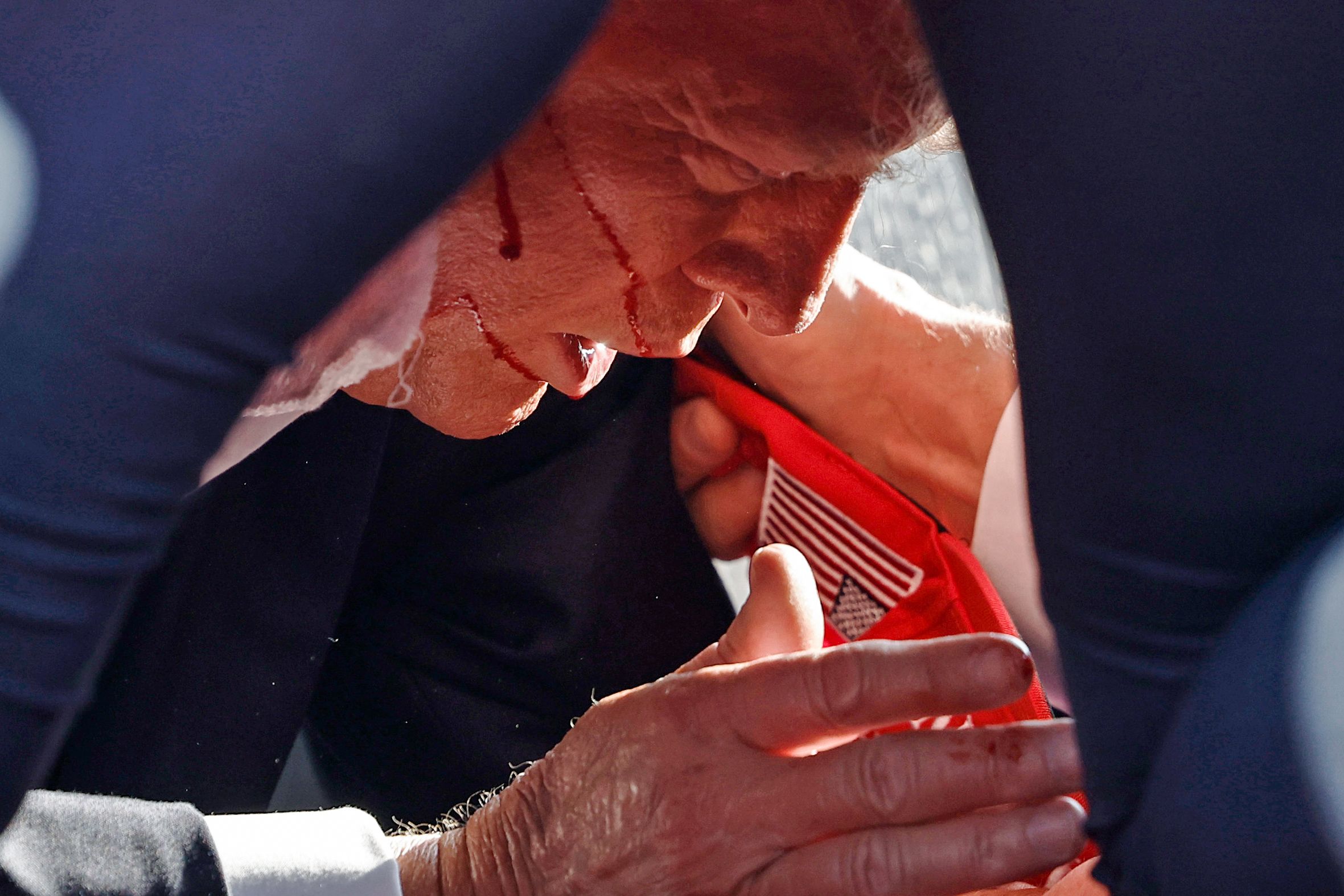 Donald Trump on the floor of the stage with a bloody face